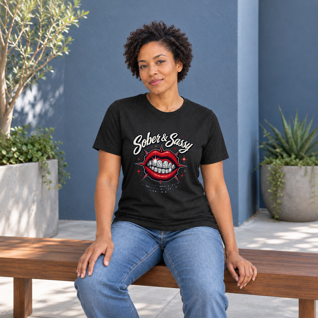 AI fashion mockup of a model seated on a wooden bench in a slate-blue courtyard wearing the black Sober & Sassy graphic T-shirt from Recovery Merch.